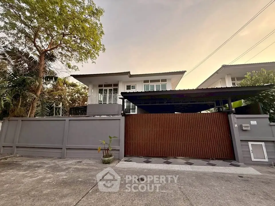 Modern two-story house with gated entrance and lush greenery