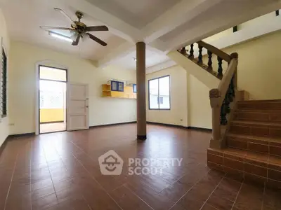 Spacious open-plan living area with staircase and ceiling fan, ideal for family gatherings.