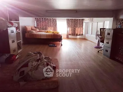 Spacious bedroom with wooden flooring and large windows for natural light.