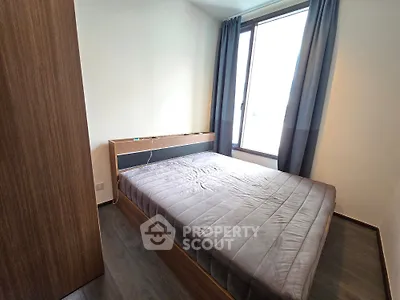 Modern bedroom with large window and stylish wooden furniture, perfect for natural light lovers.
