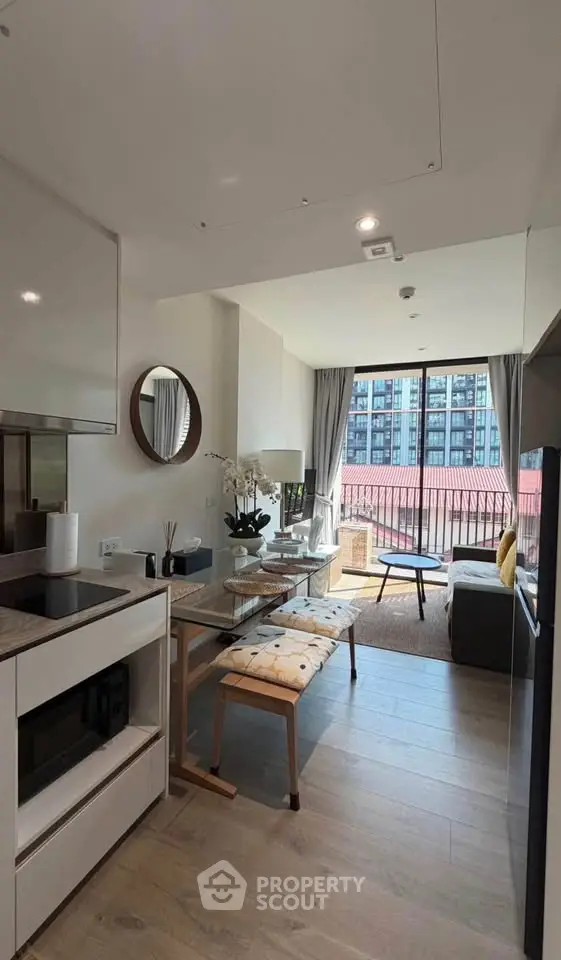 Modern open-plan living room with stylish decor and large windows leading to a balcony with city views.