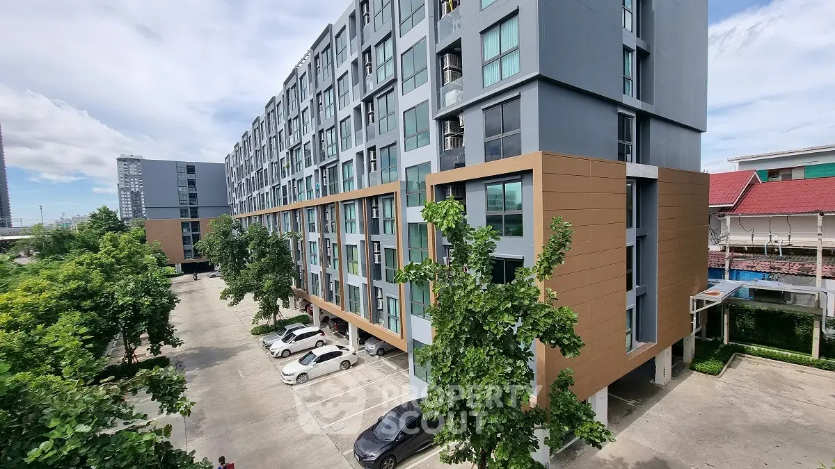 Modern apartment building with spacious parking area and lush greenery