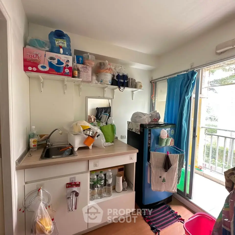 Compact kitchen with balcony access, featuring storage shelves and modern appliances.