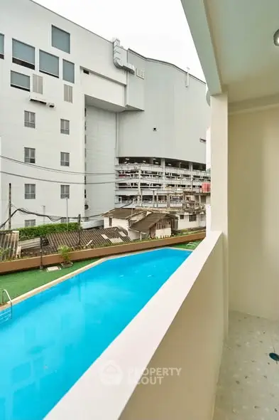 Modern apartment balcony with pool view in urban setting