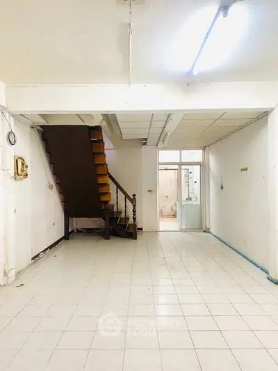 Spacious interior with tiled flooring and staircase, ideal for renovation or customization.