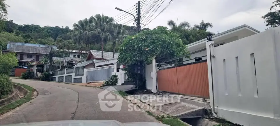 Charming hillside residential area with modern gated homes and lush greenery.