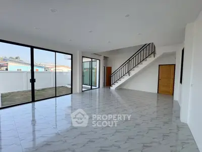 Spacious modern living room with large windows and elegant staircase