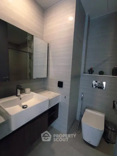 Modern bathroom with sleek fixtures and stylish design, featuring a contemporary sink and toilet.