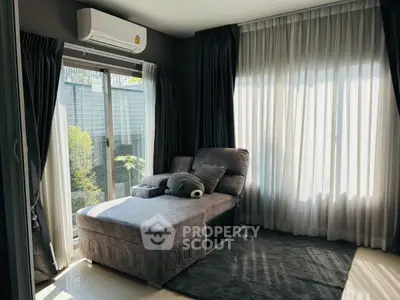 Cozy living room with plush gray sofa and large windows offering natural light.