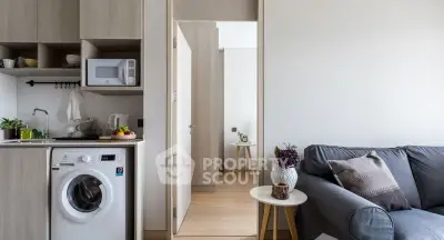 Modern apartment interior with compact kitchen and cozy living area featuring a washing machine and stylish decor.