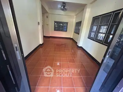 Spacious tiled room with multiple windows and sliding doors, ideal for versatile use.