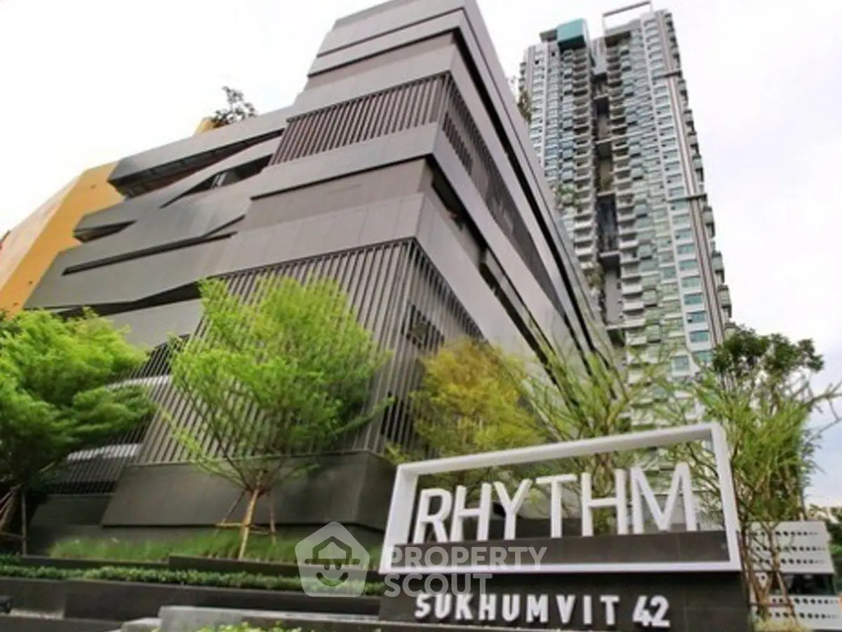Modern high-rise building with sleek architecture at Rhythm Sukhumvit 42, surrounded by lush greenery.