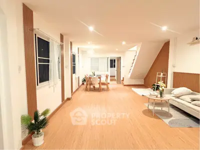 Spacious open-plan living and dining area with modern decor and wooden flooring.