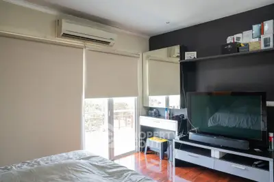 Modern bedroom with large TV and air conditioning, featuring sleek furniture and natural light.