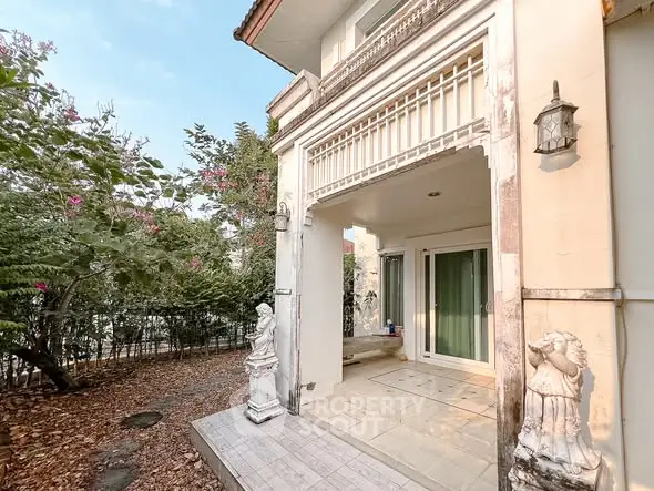 Charming exterior view of a classic home with elegant statues and lush greenery.