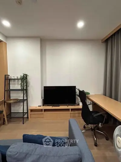 Modern living room with sleek furniture and a cozy workspace setup, perfect for urban living.