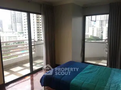 Spacious bedroom with large windows and city view, featuring a cozy bed and access to a private balcony.