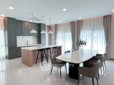 Luxurious open-layout kitchen and dining area with modern furnishings and elegant lighting.