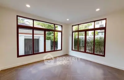 Spacious empty room with large windows and elegant flooring, perfect for customization.