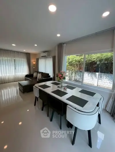 Spacious modern living room with elegant dining area and large windows offering natural light.