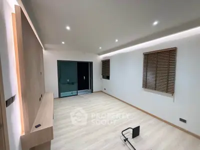 Spacious modern living room with wooden flooring and sliding glass doors leading to a balcony.