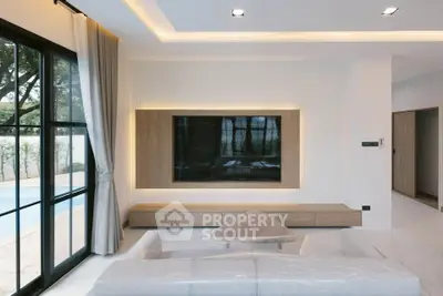 Modern living room with large window and pool view, featuring sleek furniture and ambient lighting.