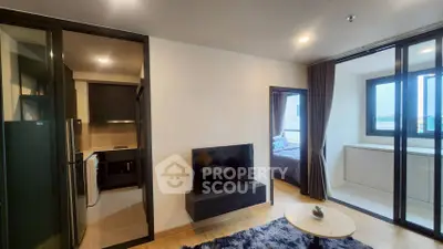 Modern apartment interior with open living area, kitchen, and bedroom view.