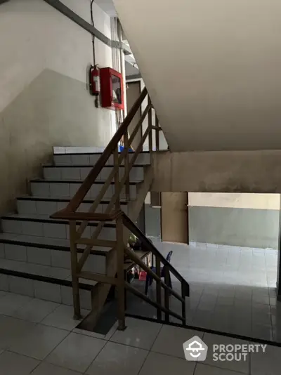 Staircase in a residential building with tiled steps and wooden railing