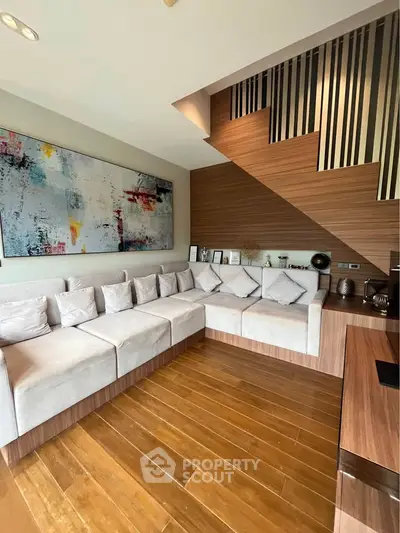 Modern living room with stylish wooden flooring and contemporary art, featuring a cozy sectional sofa and elegant decor.