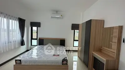 Spacious bedroom with modern furniture and large windows offering natural light.