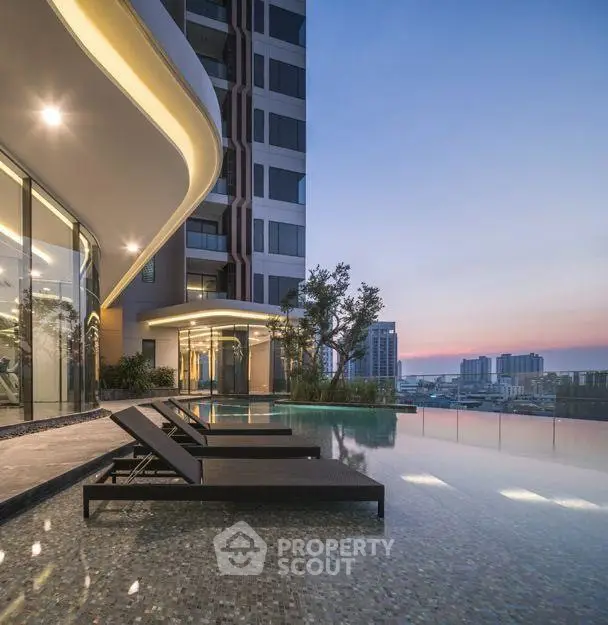 Luxurious high-rise building with stunning pool and city view at sunset.