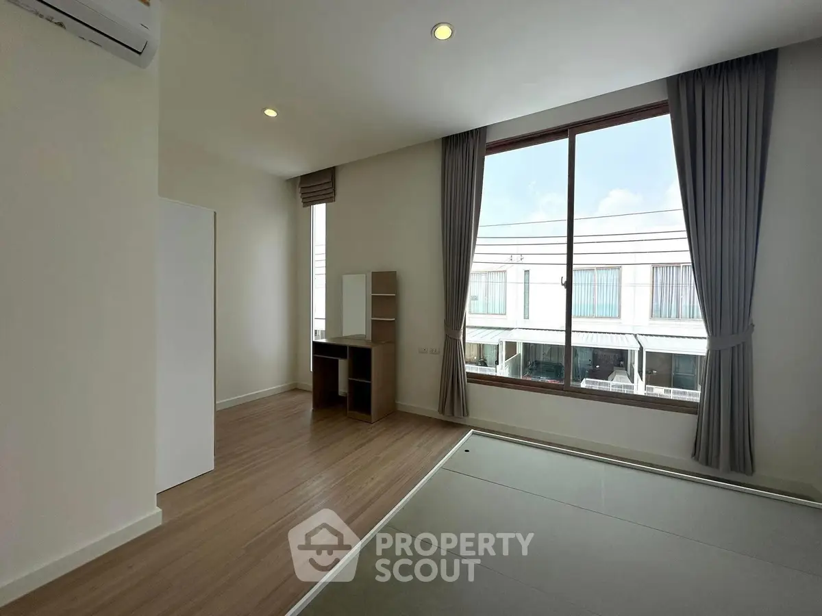 Spacious modern room with large window and wooden flooring, perfect for natural light lovers.