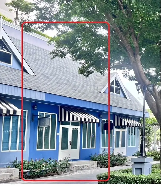 Charming blue building with striped awnings and lush greenery, perfect for commercial use.