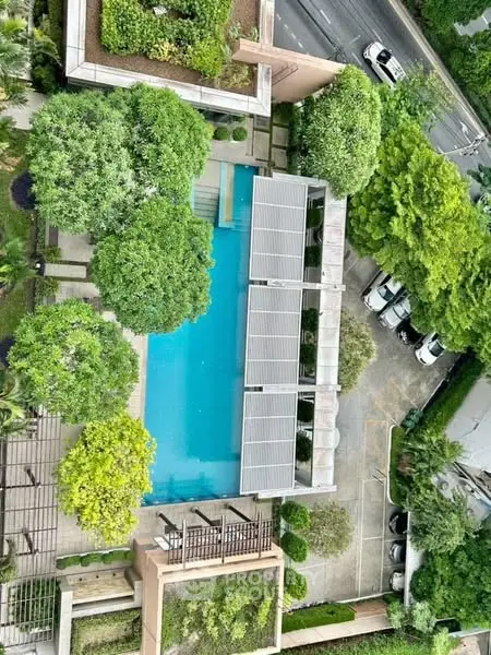 Stunning aerial view of a luxurious pool surrounded by lush greenery and modern architecture.