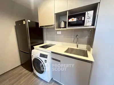 Modern compact kitchen with appliances including fridge, washing machine, and microwave in sleek design.
