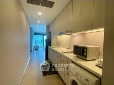 Modern kitchen with sleek cabinetry, integrated appliances, and open layout leading to a bright living area.