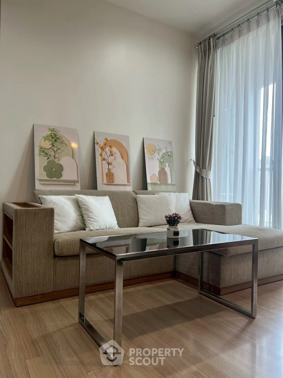 Modern living room with stylish sofa, glass coffee table, and elegant decor in a bright, airy space.
