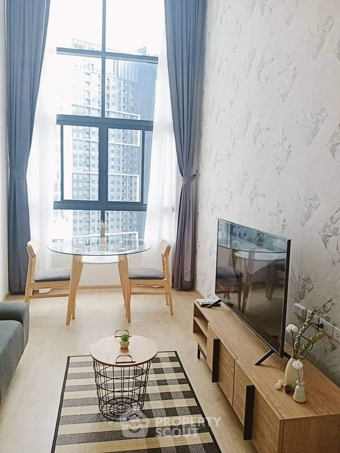 Modern living room with high ceilings, large windows, and stylish decor in urban apartment.