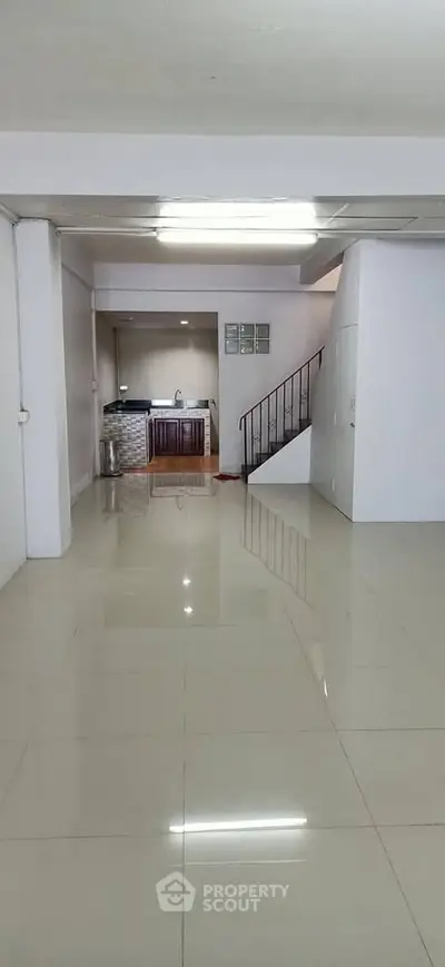 Spacious open-plan interior with sleek tiled flooring and modern staircase.