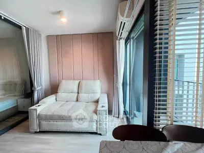 Modern living room with plush sofa and large windows offering natural light and city views.