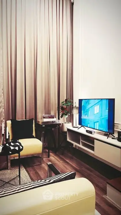 Modern living room with stylish furniture and large TV, featuring elegant curtains and wooden flooring.