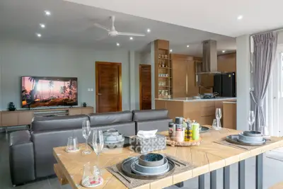 Modern open-plan living room with stylish kitchen and dining area, featuring sleek furniture and contemporary decor.