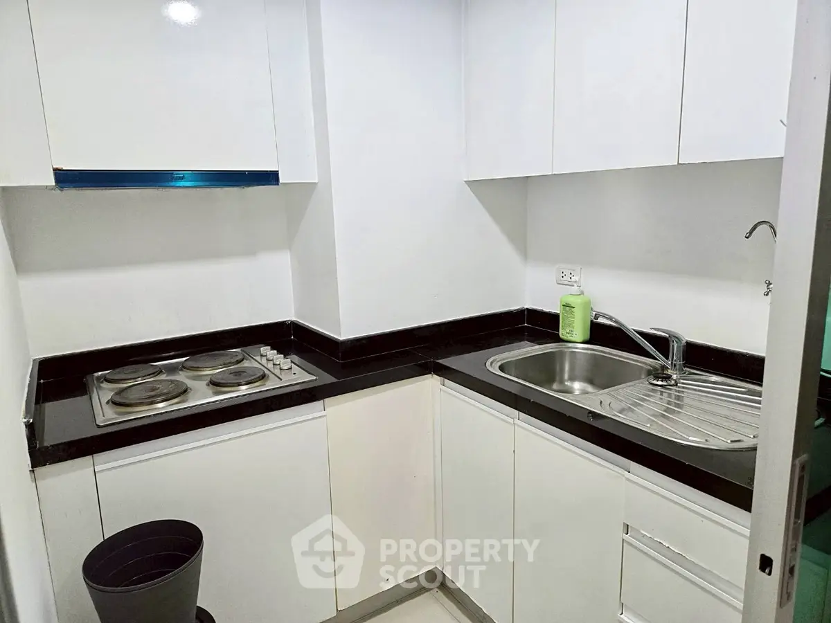 Modern compact kitchen with sleek white cabinets and electric stove
