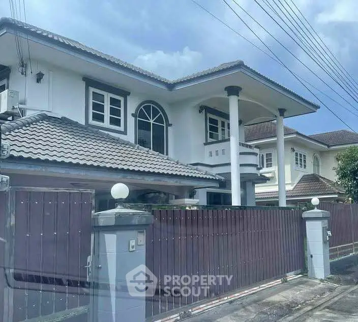 Elegant two-story house with tiled roof and spacious balcony in a serene neighborhood.