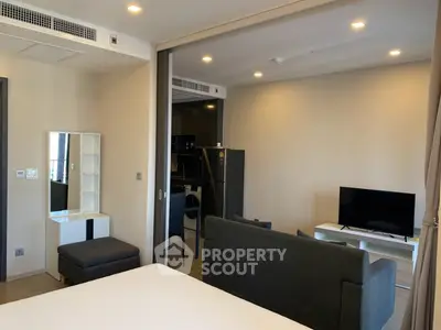 Modern studio apartment with sleek furniture and open layout, featuring a cozy living area and compact kitchen.