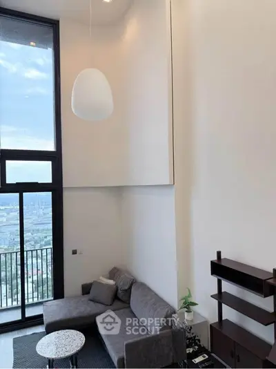 Modern living room with high ceiling and large windows offering stunning city views.