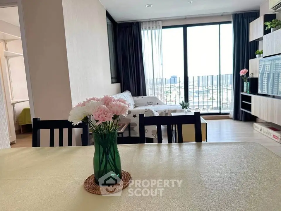 Modern living room with large windows and city view, featuring stylish decor and natural light.