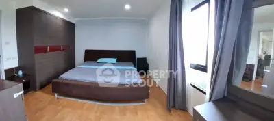 Spacious bedroom with modern furnishings and large window for natural light.