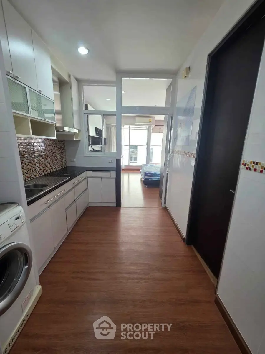 Modern kitchen with sleek cabinetry and washing machine in stylish apartment