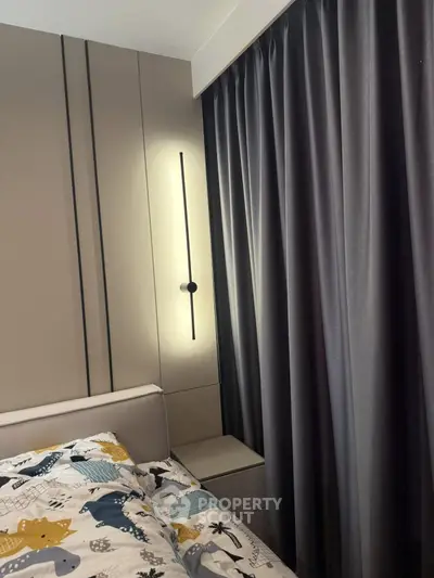 Modern bedroom with stylish lighting and elegant curtains, featuring a cozy bed with playful bedding.